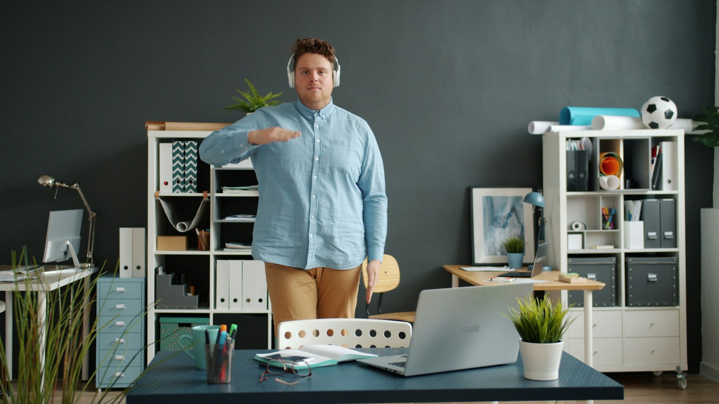 Man wearing headphones gestures in a modern office